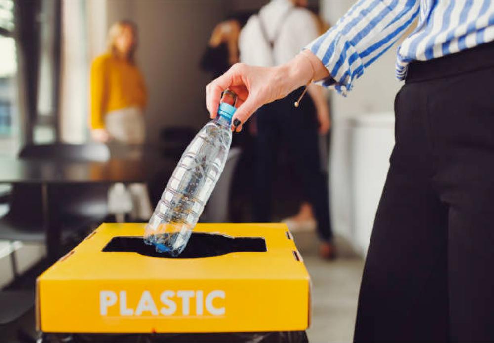 Somebody placing a plastic bottle in a plastic recycling bin